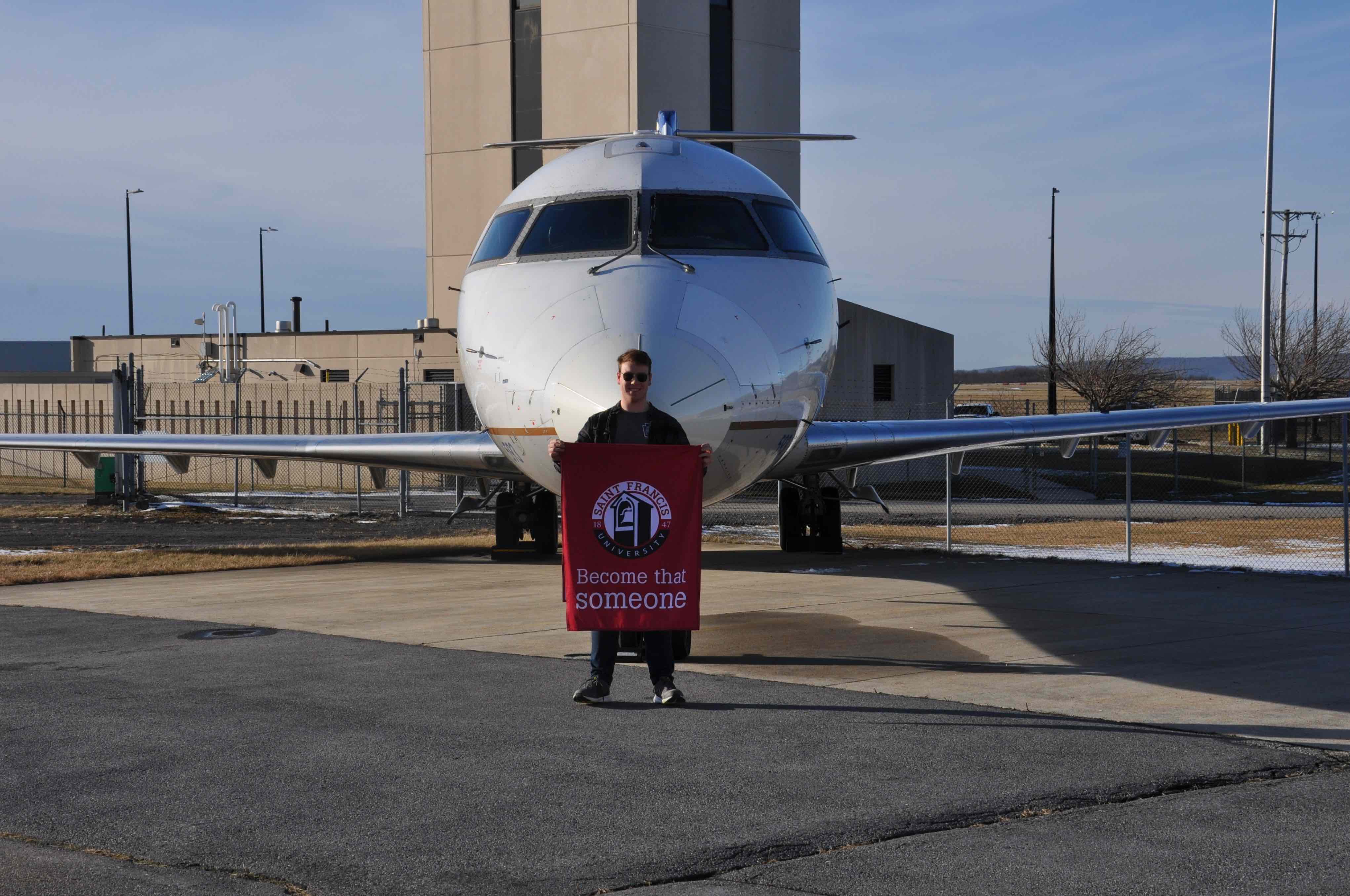 Saint Francis University student Hugh Flanagan stands in front of a CRJ200 airframe donated to SFU by SkyWest Airlines to be used as part of the future Aviation Technician program 