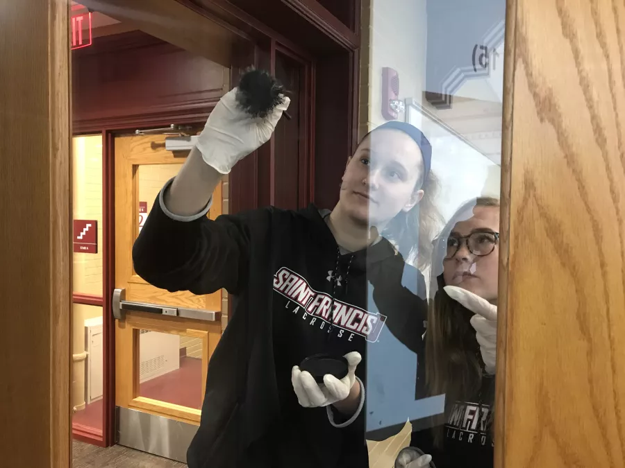 students lifting fingerprints off of a classroom door in Schwab Hall for the Criminal Investigations Class