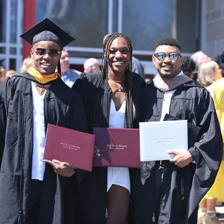 Three graduates holding SFU diplomas