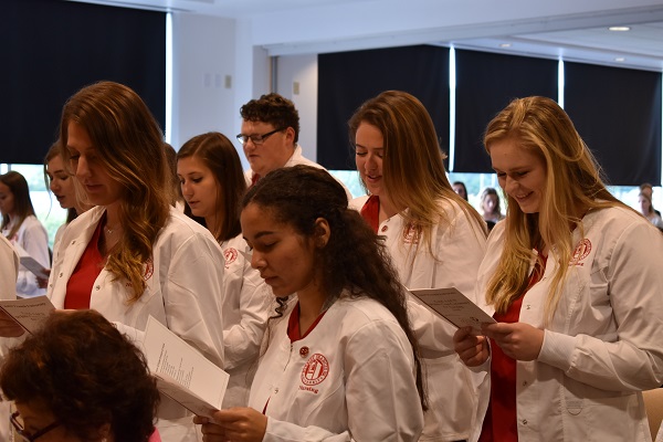 Nursing students say a prayer during the White Coat Ceremony